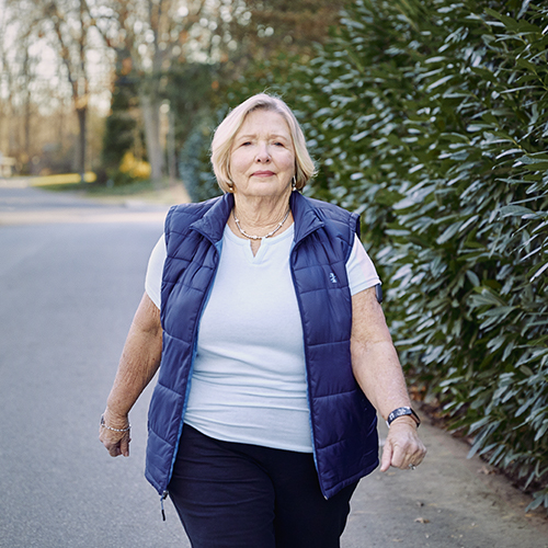 Donna che cammina all’aperto indossando il suo CGM Eversense con tecnologia con sensore del glucosio.