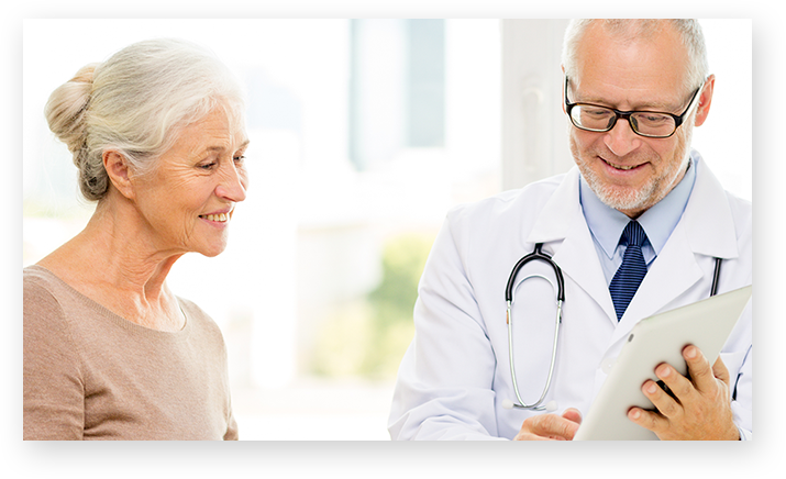 Paziente e medico in piedi l’una accanto all’altro mentre guardano un tablet.